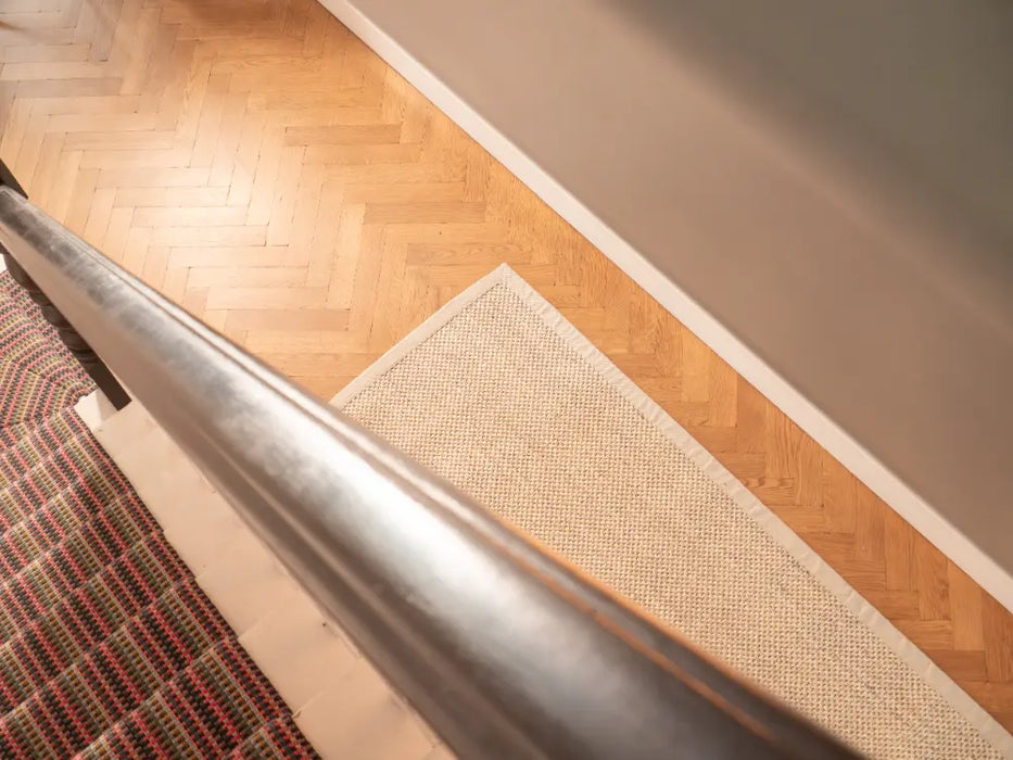 Photo By Biff | Transition from wooden floor to carpeted area with a metal handrail and sisal Rug