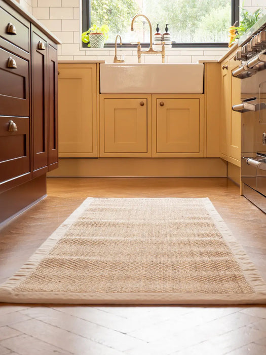 Photo By Biff | Modern kitchen with wooden cabinets, a sisal rug on the floor, and a window in the background.
