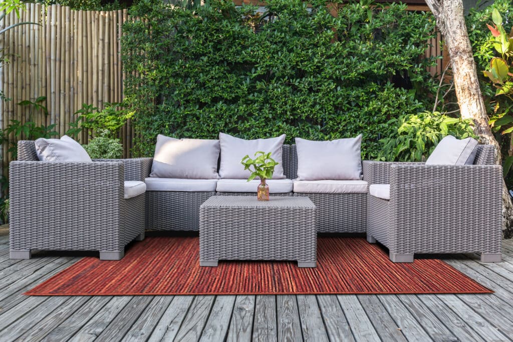 Large terrace patio with rattan garden furniture in the garden on wooden floor.