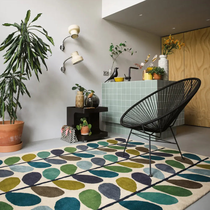 An Orla Kiely blue and green rug features in the centre of a room with a modern black chair and tiled bar area. 