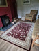 Photo By Mike. | Living room with a patterned red rug, wooden armchair, and fireplace.