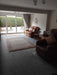Photo By A Lianne T | dark brown leather recliner chair in a living room with a striped area rug, a brown leather loveseat, and large glass doors looking out onto a garden.