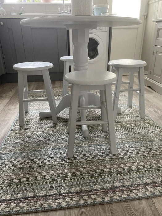Photo By Nicola T. | White round table with three stools on a patterned rug in a kitchen.