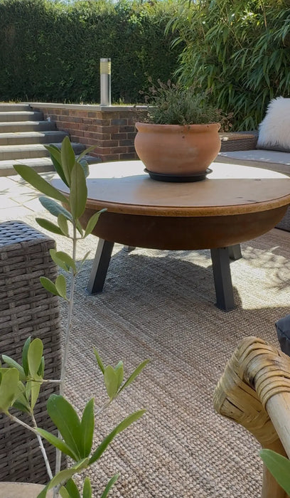 Photo By Fray at Home | Outdoor patio rug with wooden table, potted plant, and garden furniture.