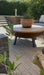 Photo By Fray at Home | Outdoor patio rug with wooden table, potted plant, and garden furniture.