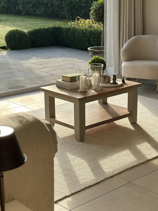 Photo by @Ourruralnest |Coffee table with decorative items in a sunlit room with a view of a garden.