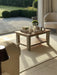 Photo by @Ourruralnest |Coffee table with decorative items in a sunlit room with a view of a garden.