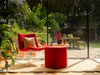 Photo by David Y | Red chair and ottoman on a patio with plants and a glass door in the background On a scalloped rug