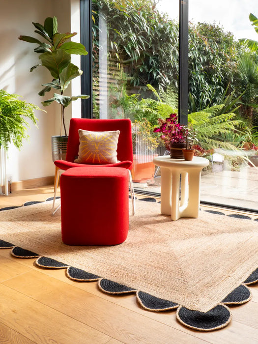 Photo by David Y | Modern living room with red armchair, ottoman, and decorative plants and scalloped Rug