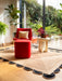 Photo by David Y | Modern living room with red armchair, ottoman, and decorative plants and scalloped Rug