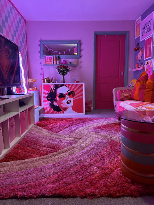 Photo by @aggielang | Colourful room with pink walls, a red door, and a patterned rug.