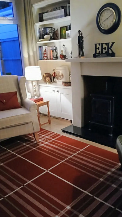 Kathleen M. | Living room with a fireplace, bookshelf, and red and white checkered Tartan rug.