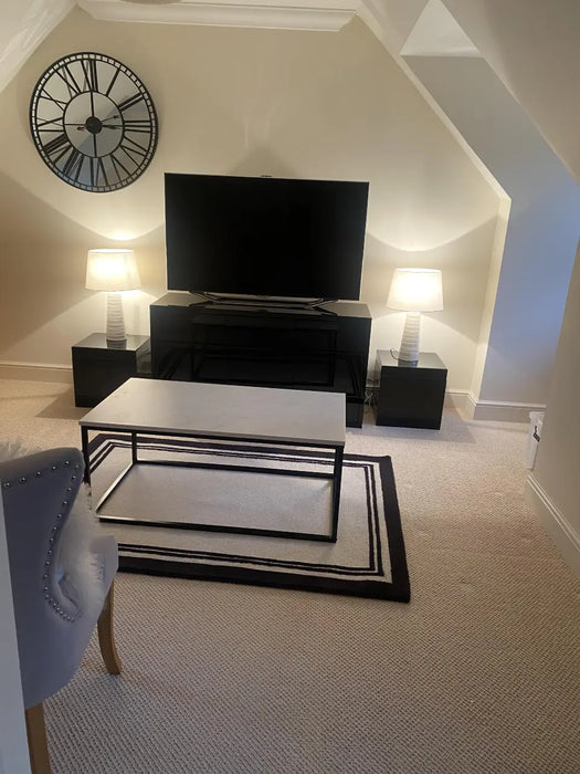 Photo By Joyce N. | Modern living room with a television, clock, and table.