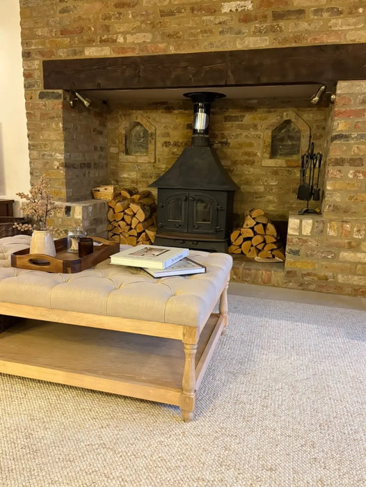 Photo By @renovatingtudorlodge | Living room with a brick fireplace, wooden bench, and firewood.