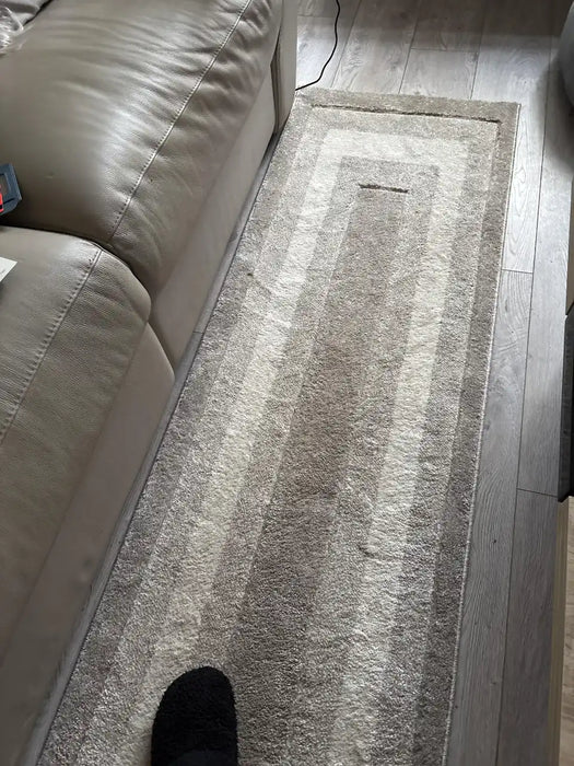 Photo By Deiana R. |Gray area rug on a wooden floor next to a beige sofa.