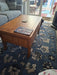 Photo By Sylv | Wooden coffee table with a decorative item on a patterned blue rug in a living room.